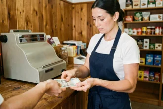 Caissière comptant des billets de banque pour rendre la monnaie à un client dans une boutique indépendante